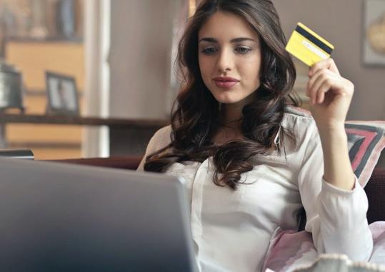 Lady at a laptop computer holding a credit card.